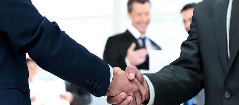 Two men in business suits shaking hands.